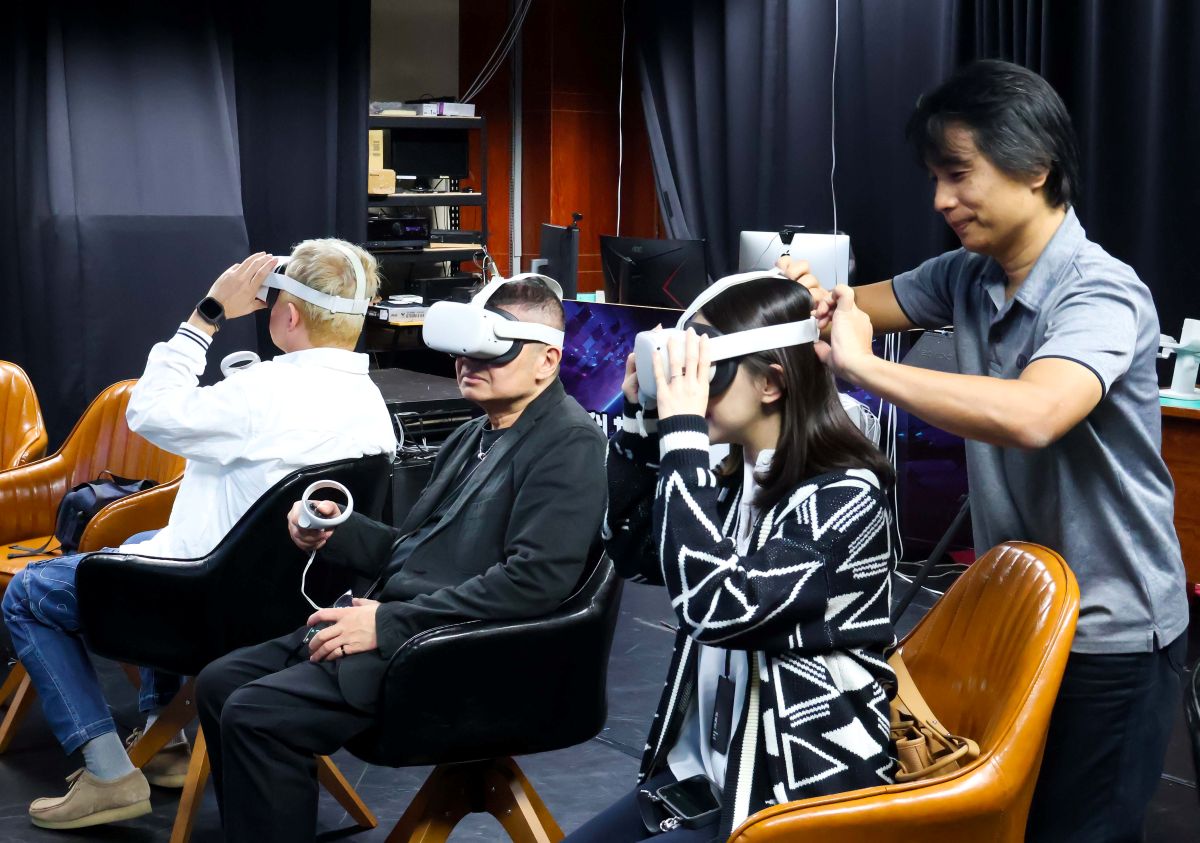 高雄流行音樂中心執行長丁度嵐（中）體驗義守大學元宇宙科技藝術設計中心設備。